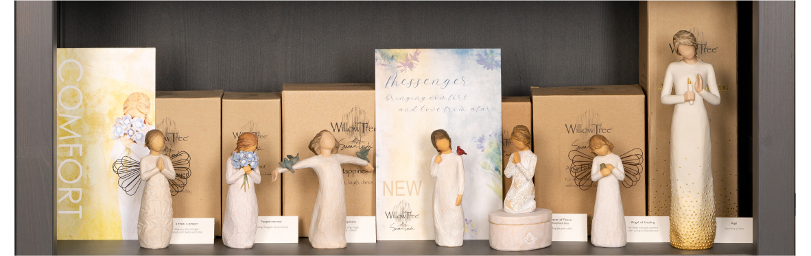 Willow Tree hand carved figurines displayed on a shelf next to a sign with the word LOVE
